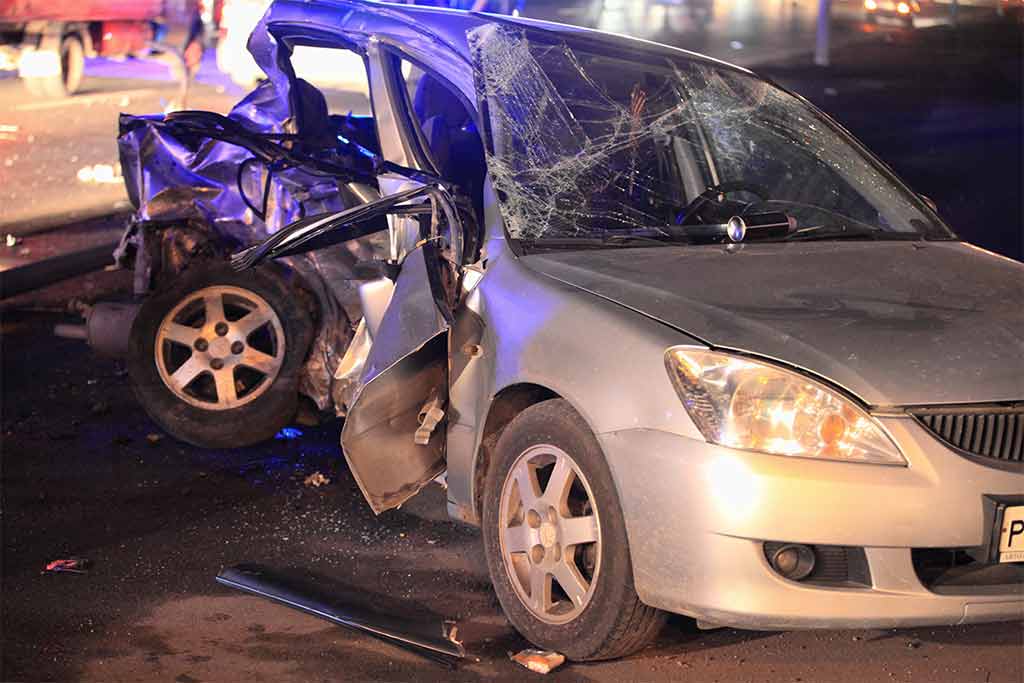 car with major damage to the left hand side at night
