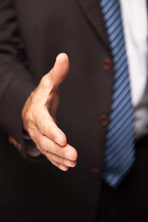 A lawyer xtending a handshake to the viewer